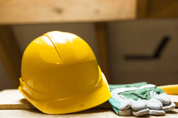 Желтый защитный шлем и перчатки на рабочей поверхности чердака
 - Фото, изображение