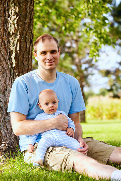 Happy father sitting with newborn son on grass - Photo, Image