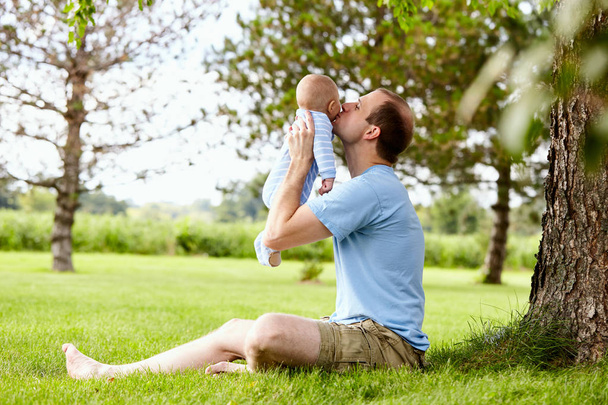 Happy young father kissing little son in park - Foto, afbeelding