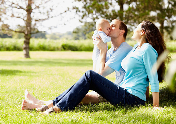 Happy man sitting with wife and kissing little son - Photo, Image