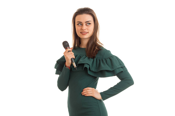 Portrait of a young charming singer with a microphone in a green dress - Фото, изображение