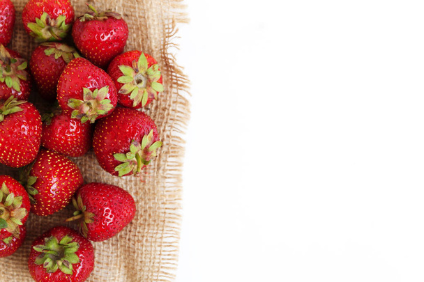 A pile of fresh juicy strawberries lies on an old sackcloth, iso - Фото, изображение