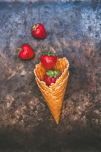 Fresh juicy strawberries in a waffle cone on a dark old backgrou - Foto, afbeelding