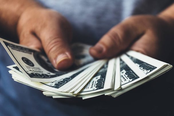 Człowiek przytrzymanie banknotów dolara usa w ręce rozłożone przez wentylator, dzięki gotówce pieniędzy do sukcesu. Selektywny fokus na pieniądze - Zdjęcie, obraz