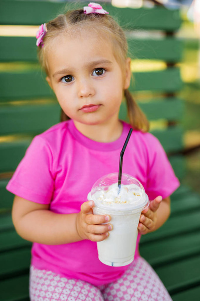 Little girl drinking milkshake through a straw - Photo, Image