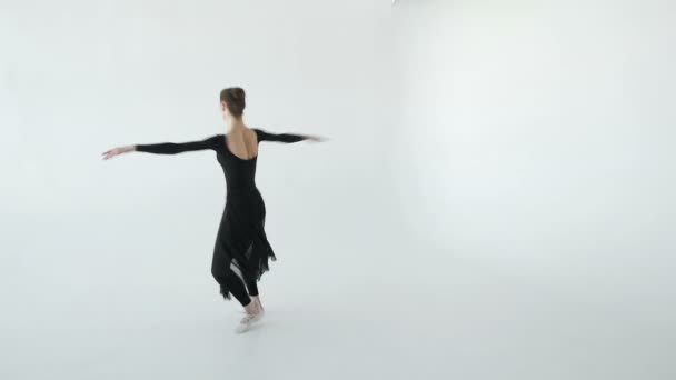Attractive brunette ballerina in white pointe dancing in a white dance studio 20s 1080p slow motion - Filmati, video