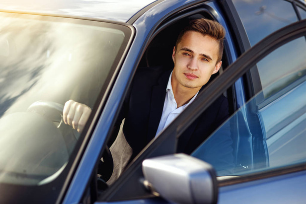 Attrayant bel homme élégant dans un costume d'affaires au volant d'une voiture chère
 - Photo, image