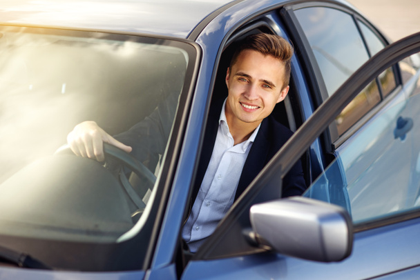 Aantrekkelijke knappe Glimlachende man in een pak een dure auto rijden - Foto, afbeelding