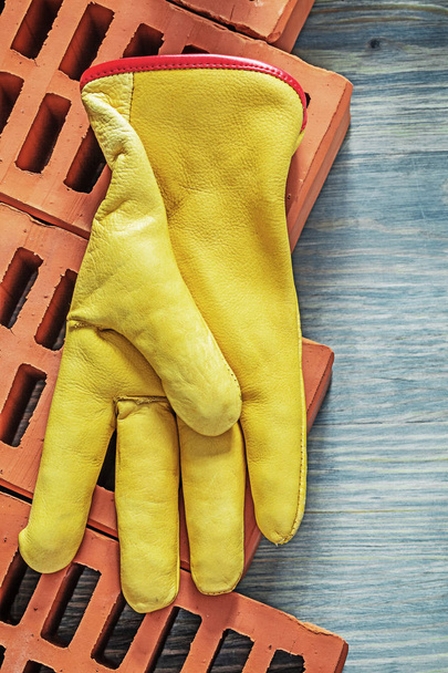 Red bricks leather safety gloves on wooden board top view buildi - 写真・画像