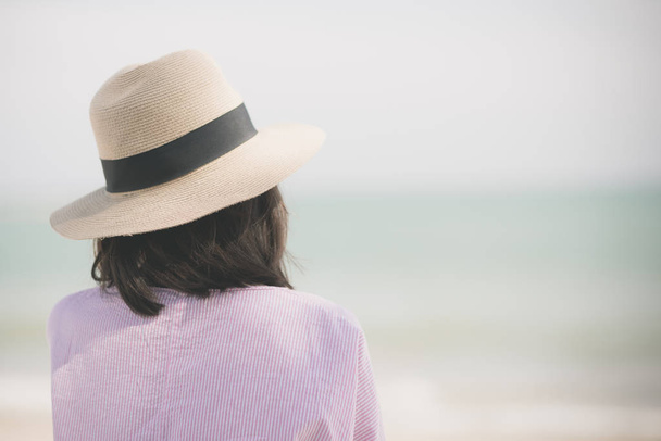Back of woman wearing straw hat relax on the beach - Foto, afbeelding