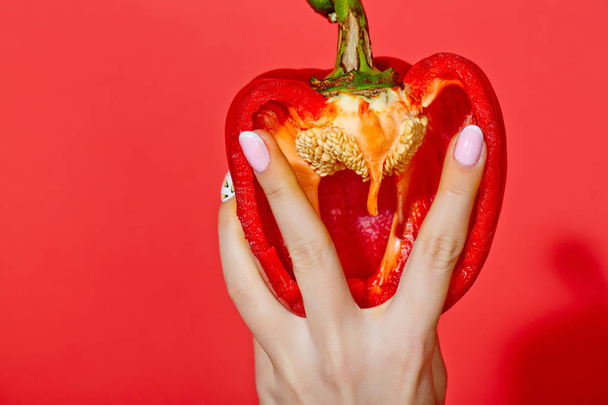 paprika in hand of girl on red background - Zdjęcie, obraz