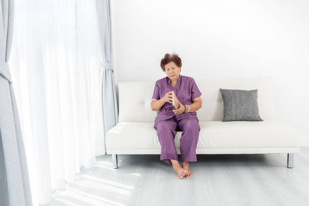 Asian senior woman open brown book and sitting on sofa near wind - Foto, immagini