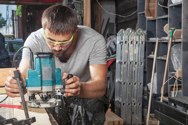 homem bordas de madeira com uma máquina de moagem
 - Foto, Imagem