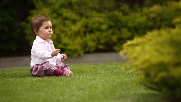 Cute little baby-girl learning to crawl on the green meadow in the city park. - Footage, Video