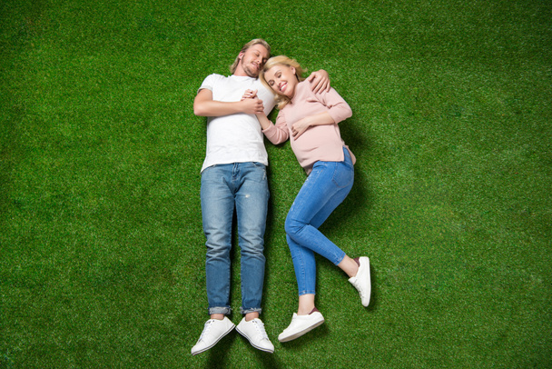 pregnant woman with boyfriend lying on grass - Zdjęcie, obraz