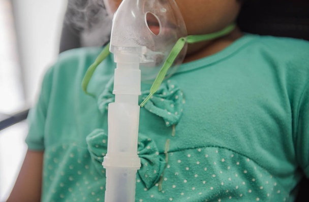 Young woman doing inhalation nebulizer with smoke from oxygen mask in the hospital - Photo, Image