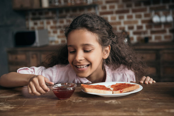 girl looking at jam in bowl - Photo, Image