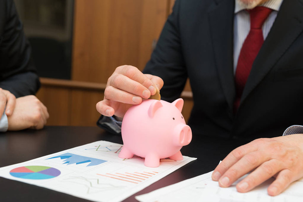 Businessman putting money in piggy bank - Фото, изображение