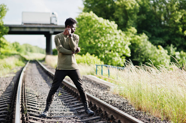Cool black african american man walking and posing on railway in - Fotó, kép