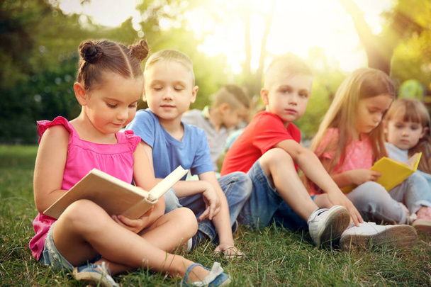 Cute children reading books in park. School holidays concept - Fotó, kép