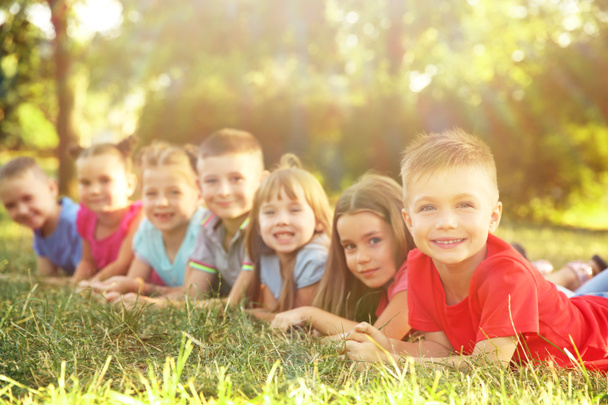 かわいい子供たちは、公園の草の上に横たわる。学校休日の概念 - 写真・画像