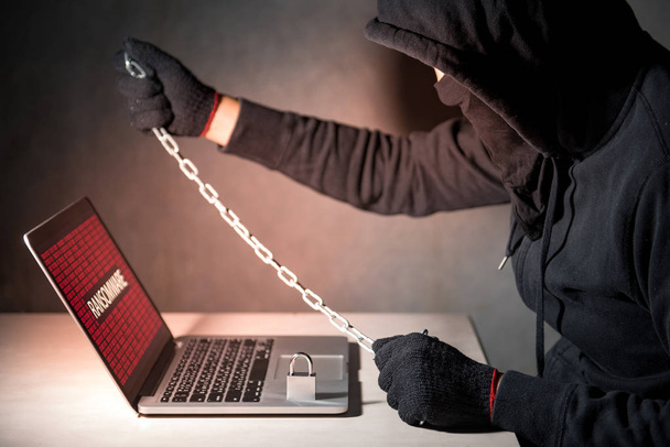Male hacker locking computer by using chain and padlock - Photo, Image