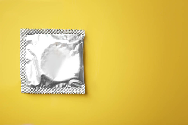 Wrapped condom on color background - Valokuva, kuva