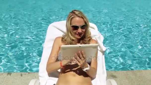 Girl with a tablet by the pool. Woman with a tablet computer on the background of the pool. - Felvétel, videó