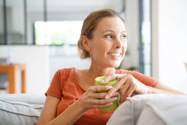 woman relaxing in sofa and drinking tea - Zdjęcie, obraz