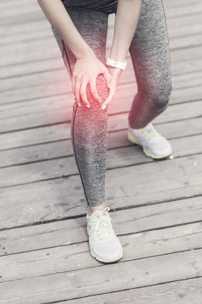 Corredor atleta femenina tocando la rodilla con dolor al aire libre
 - Foto, imagen