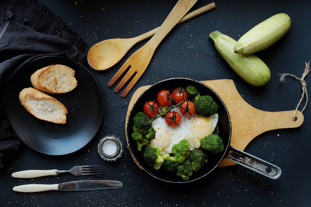 Fried eggs with broccoli and cherry tomatoes in a frying pan  - Fotografie, Obrázek