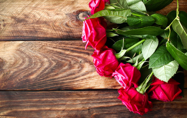 Bouquet de roses rouges sur fond bois. Retour sur la Saint Valentin
 - Photo, image