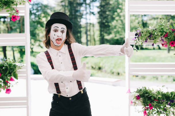 Pantomime artist posing near pots of flowers - Photo, Image
