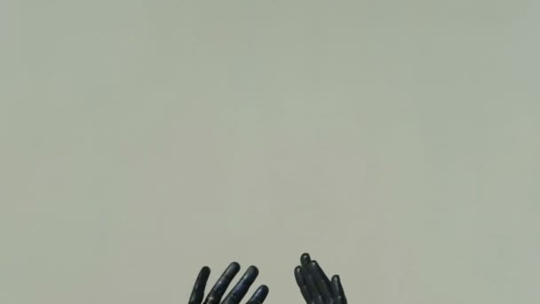 Erilliset kädet harmaalla pohjalla täysin peitetty mustalla maalilla, koristeltu sinisillä paljeteilla
 - Materiaali, video