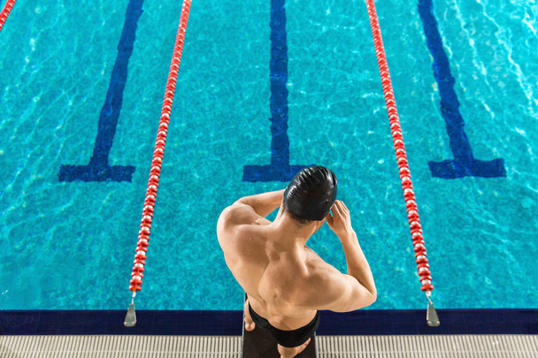 Rear view of a man preparing swimming goggles - Fotó, kép
