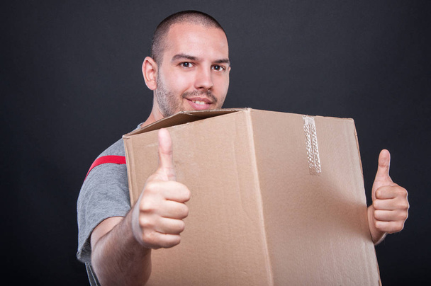 Парень, держащий коробку, показывает двойной подобный жест
 - Фото, изображение
