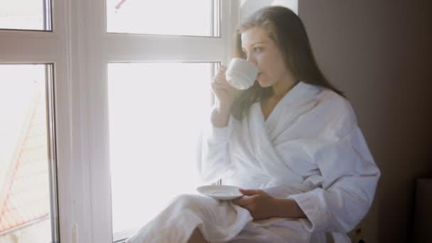 pencere kenarında oturan ve kahve içme genç kadın 4 k görüntüleri - Video, Çekim