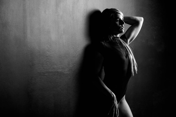 Sexy female fitness model in a studio with dramatic lighting and - Zdjęcie, obraz