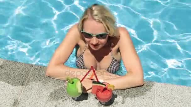 Uma mulher está a beber um cocktail na piscina. Menina bonita em um maiô com dois coquetéis
. - Filmagem, Vídeo