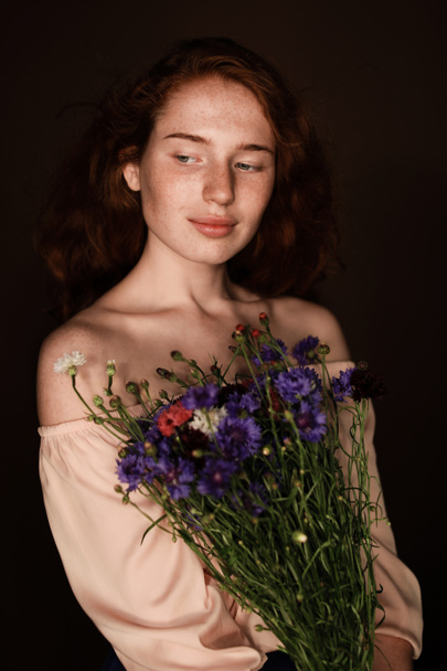 pelirroja sosteniendo flores silvestres
 - Foto, Imagen