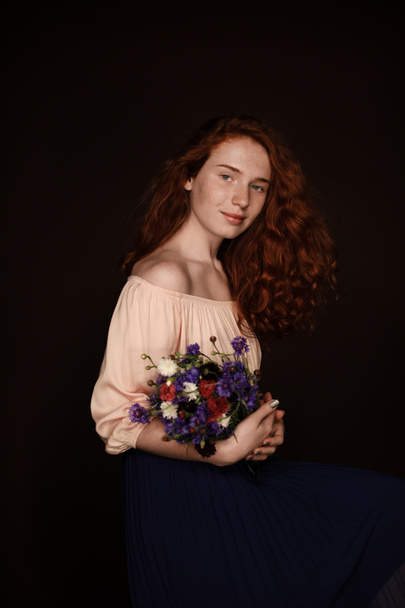 redhead girl holding wild flowers - Фото, изображение