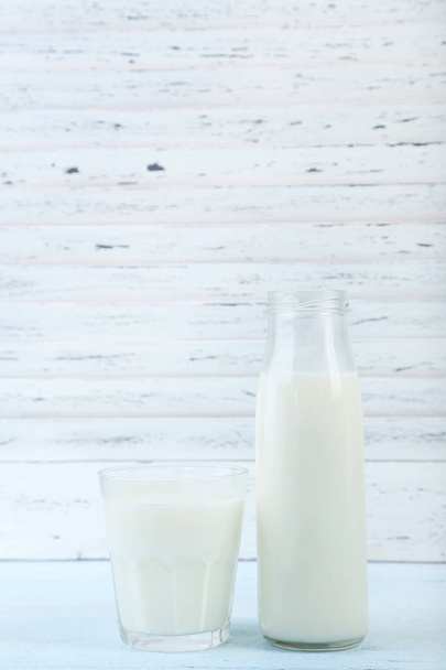 Glass and bottle of milk on wooden table - Foto, afbeelding
