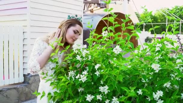Young bride smels flowers on the bush during the summer - Felvétel, videó