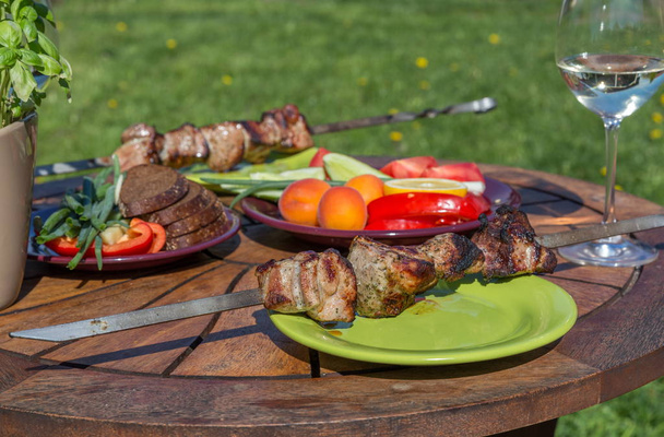Valikoima herkullista grillattua lihaa vihannesten kanssa piknikpöydällä perheen bbq-juhliin
 - Valokuva, kuva