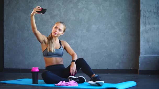 スポーツ女性はフィットネス クラブでのトレーニングの後電話で写真を取る - 映像、動画