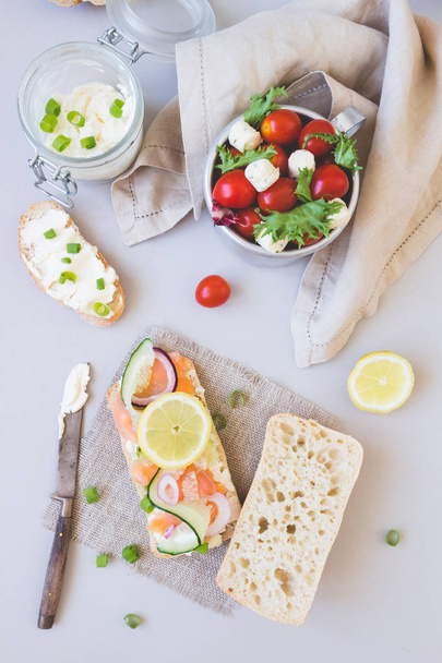 Świeży pomidor sałatka i ciabatta chleba z twarogiem i łososia na szarym tle - Zdjęcie, obraz