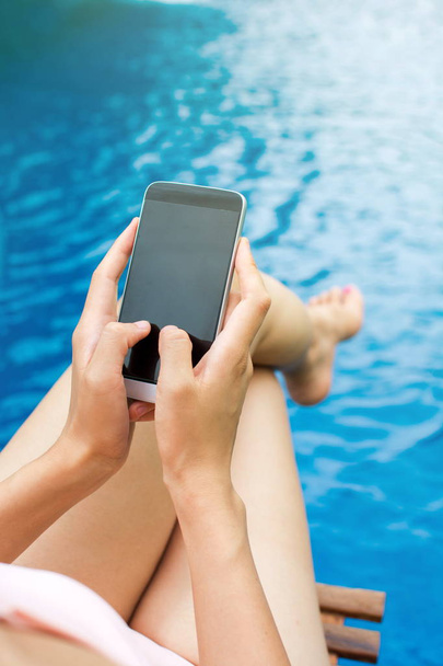 Girl using phone by the swimming pool - Zdjęcie, obraz