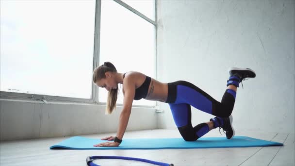 Atraktivní a sportovní dívka dělá houpačka s nohou na posílení hýždí - Záběry, video