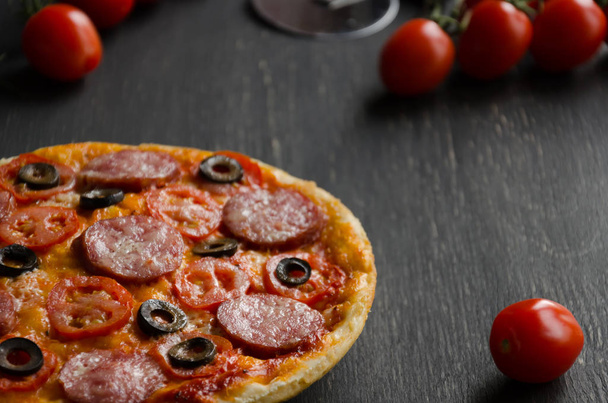 W domu pizza z salami, oliwki, pomidory i ser parmezan - Zdjęcie, obraz