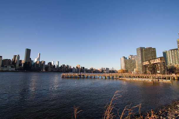 Molo na East river na Gantry Plaza State Park a budovy Manhattanu přes East river - Fotografie, Obrázek